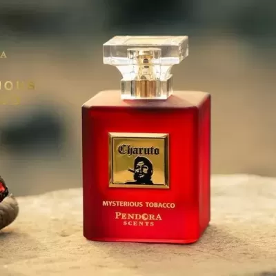 Frasco vermelho fosco de perfume Charuto ao lado de dois charutos acesos sobre rocha