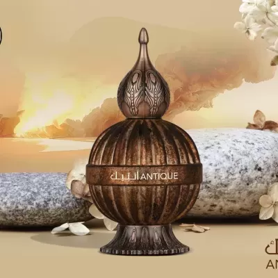 Frasco decorativo antigo de perfume com textura em tom castanho e fundo com pedras e flores.