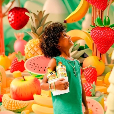 Criança segura snacks com frutas gigantes decorativas ao fundo