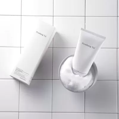 Produto Pyunkang Yul com embalagem branca e tubo num banho de espuma
