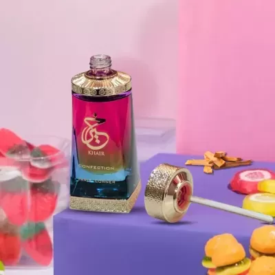 Frasco de perfume com tampa dourada sobre superfície roxa com doces ao redor