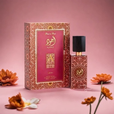 Frasco de perfume Ajwad ao lado da caixa com design vermelho e dourado e flores ao redor