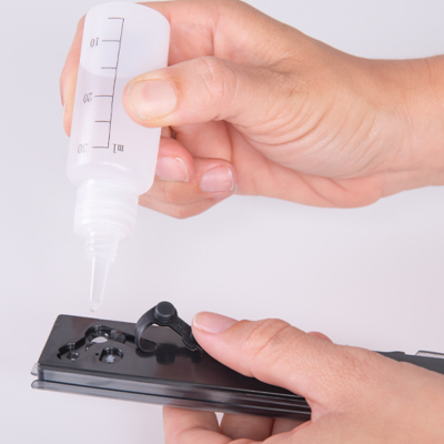 Frasco plástico transparente com graduação e peça preta com mecanismo em mãos