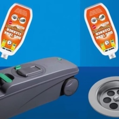 Dispositivo automático para sanita com frascos de limpeza laranja e grelha de escoamento.