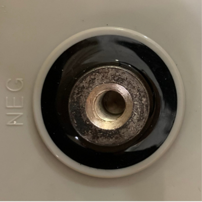 Toma elétrica circular com anel branco e centro metálico