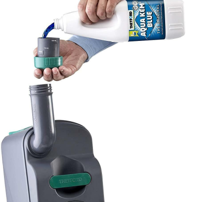 Mão a verter líquido azul de frasco THETFORD Aquakeim Blue para doseador cinzento com tampa verde junto a equipamento cinzento