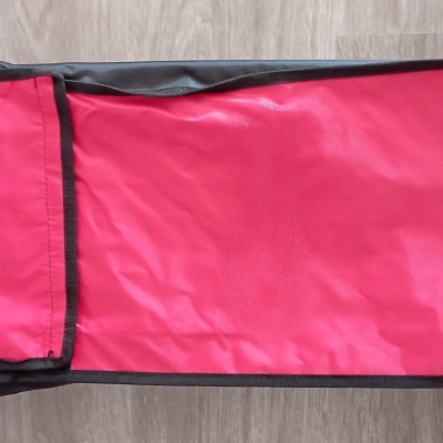 Mala de transporte vermelha e preta sobre pavimento de madeira clara