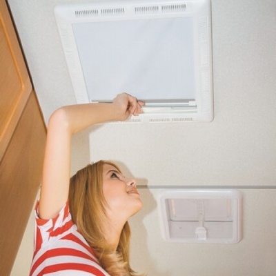 Mulher a abrir claraboia no teto interior, vestindo camiseta às riscas vermelhas e brancas