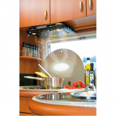 Coifa de cozinha preta com fluxo de ar desenhado, panela de inox no fogão, especiarias, pimentos e azeite em bancada de cozinha