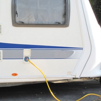 Caravana branca com risca azul e janelas com cortinas