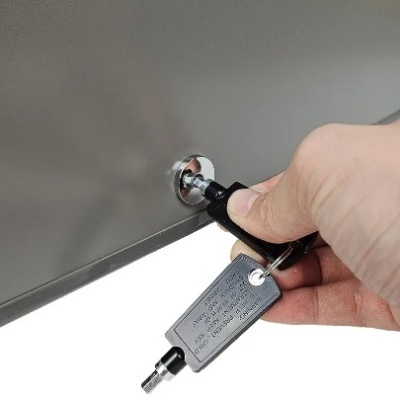 Chave com suporte preto numa porta metálica cinza com mão a segurar