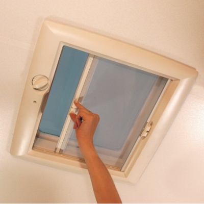 Clarabóia de teto com janela azul deslizante e rede preta, mão humana a ajustar