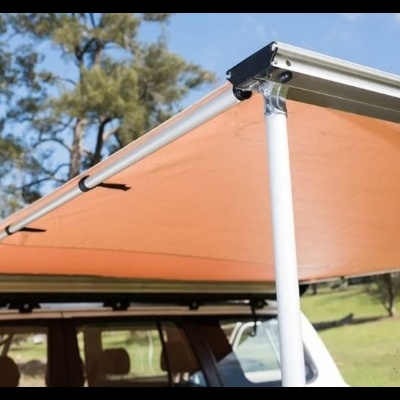 Toldo laranja em veículo branco com suportes metálicos e postes brancos em espaço exterior