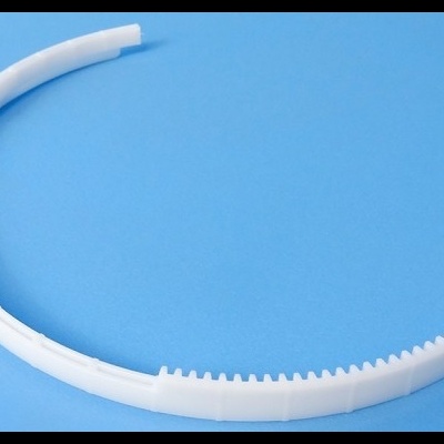 Peça plástica branca semi-circular com dentes pequenos, sobre fundo azul.