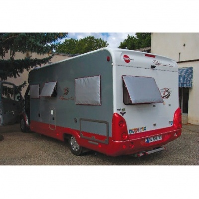 Autocaravana cinzenta e vermelha com janelas cobertas e autocolantes na traseira