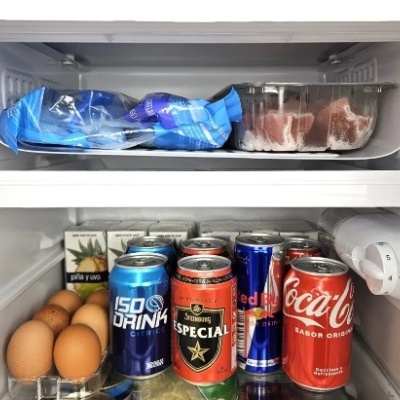 Interior de frigorífico com ovos, latas de bebidas e comida congelada