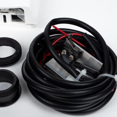 Cabo preto enrolado com fios vermelhos e pretos, peças de borracha e aparelho branco