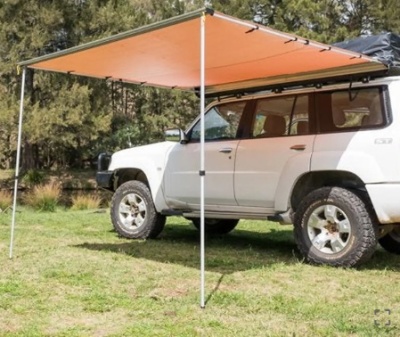 SUV branco com toldo laranja montado em estrutura metálica no tejadilho