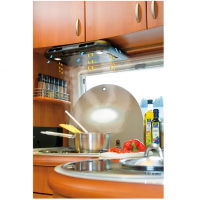 Coifa de cozinha preta com fluxo de ar desenhado, panela de inox no fogão, especiarias, pimentos e azeite em bancada de cozinha