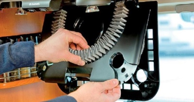 Mãos a ajustar correia em máquina com nome Dometic e prateleira com especiarias ao fundo.