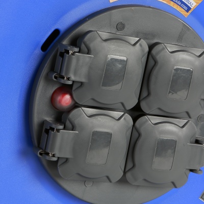Quatro tomadas elétricas cinza com tampas num suporte redondo cinza sobre superfície azul