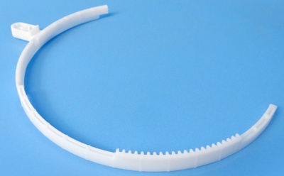 Peça plástica branca semi-circular com dentes pequenos, sobre fundo azul.