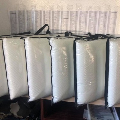 Sete almofadas brancas com bordas pretas alinhadas sobre uma mesa em ambiente de escritório