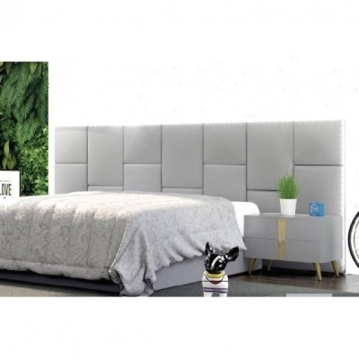 Cama de casal com cabeceira cinzenta estofada e mesa de cabeceira com vaso e figura decorativa de cão
