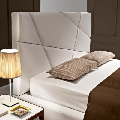 Cama com cabeceira estofada branca e roupa de cama castanha numa decoração moderna