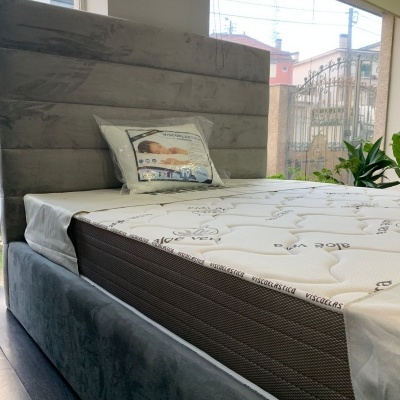 Cama estofada cinza com colchão branco estampado e almofada decorativa