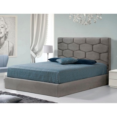 Cama de casal estofada cinzenta com colchão azul e almofadas, mesa de cabeceira branca e candeeiro