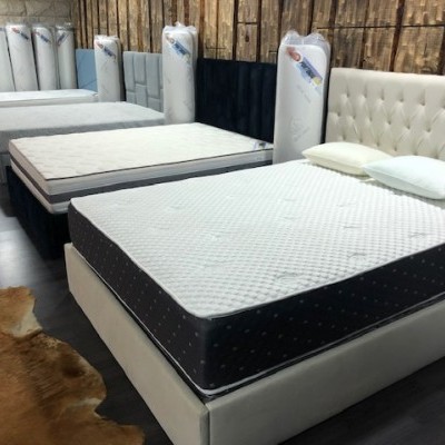 Cama com colchão branco e laterais pretas em loja com paredes de madeira