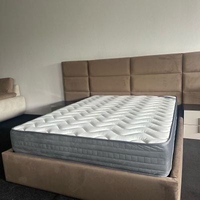 Cama de casal com colchão branco e estrutura castanha clara