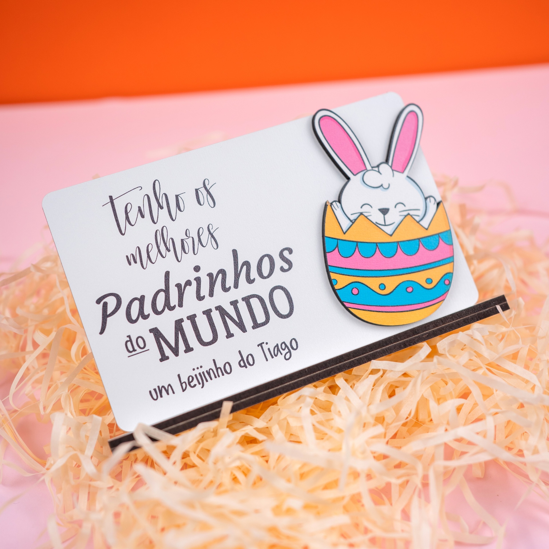 Placa Tenho o melhor Padrinho/Madrinha Cartão branco com texto preto e desenho colorido de coelho dentro de ovo colorido