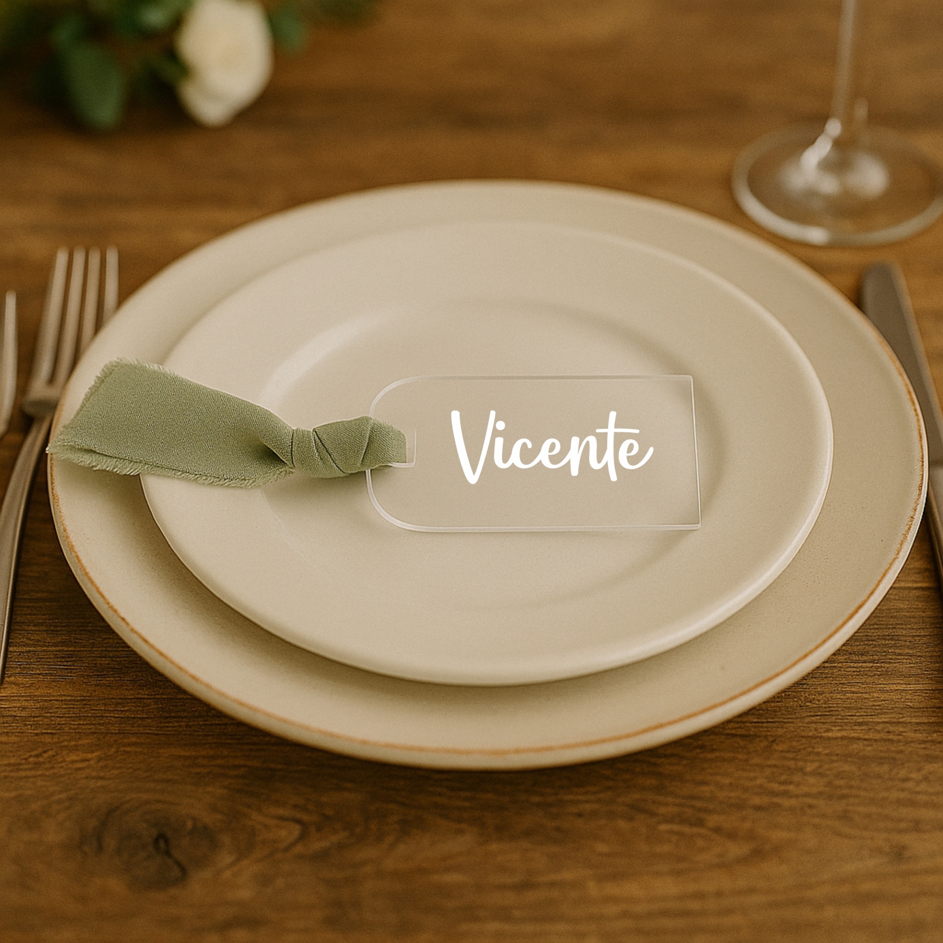 Marcador de Lugar em Acrílico com Laço de Tecido – Personalizado Etiqueta transparente para mesa com o nome Vicente em pratos brancos e guardanapo verde numa mesa de madeira