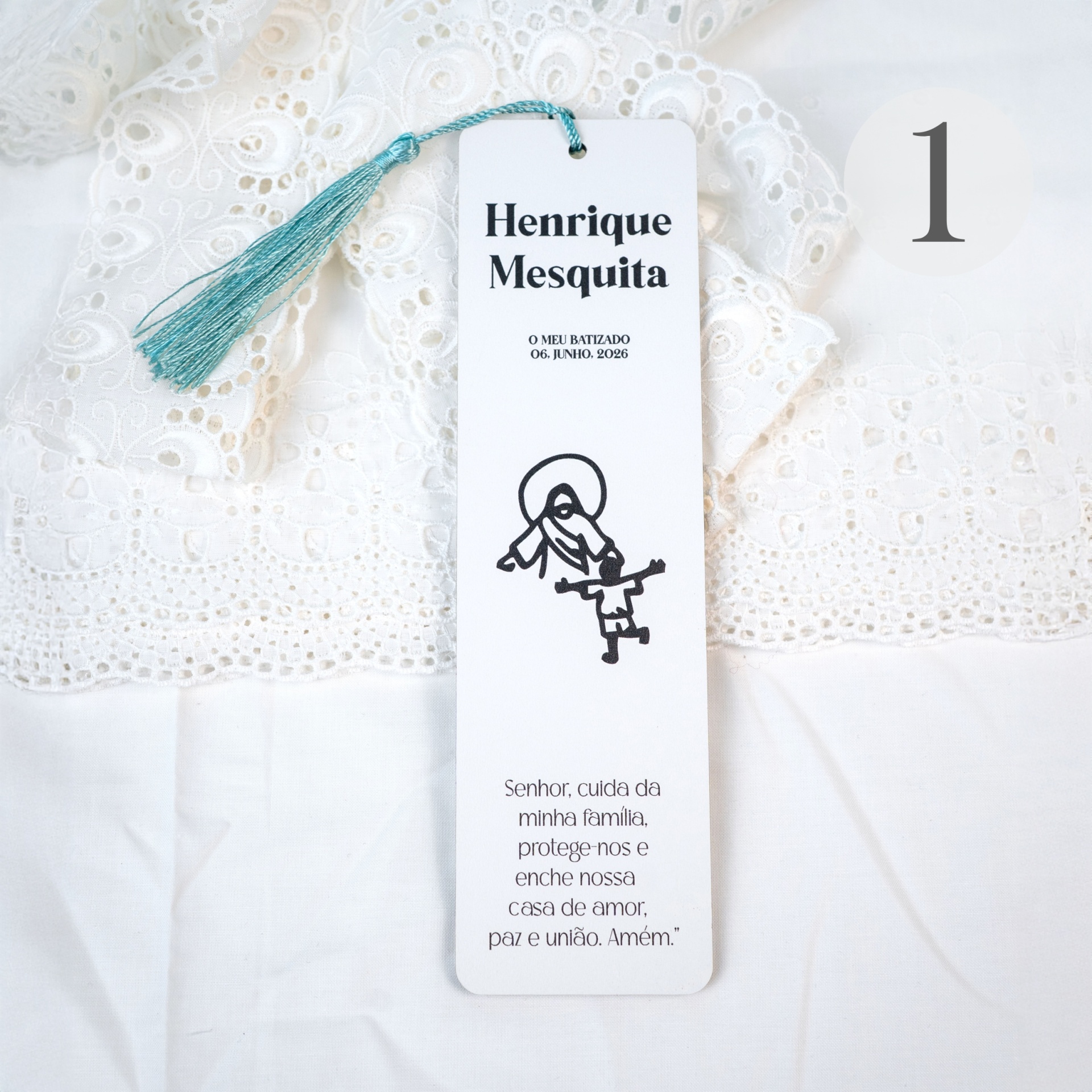 Marcador de Livro Personalizado com Dedicatória – Mod 02 Etiqueta de batizado branca com tassel azul, texto preto e tecido rendado branco ao fundo