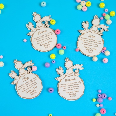 Tags de madeira personalizadas com desenho do Pequeno Príncipe e frases, fundo azul com contas coloridas