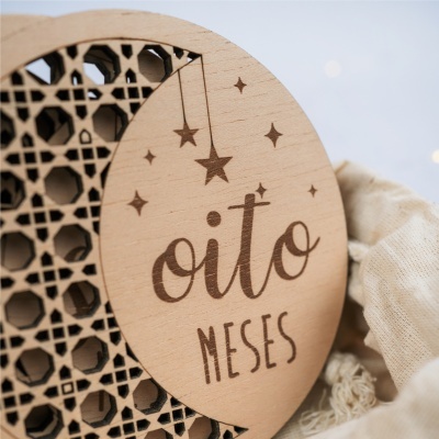 Placa redonda de madeira com gravura oito MESES e estrelas sobre tecido