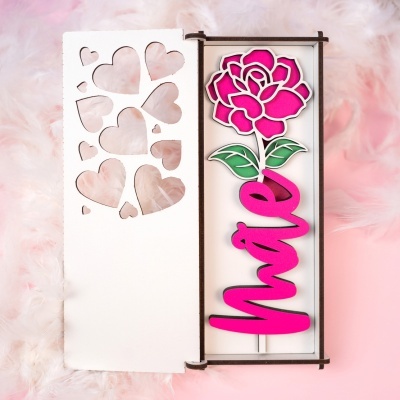 Caixa branca decorada com corações recortados e presente com flor rosa e palavra Mãe