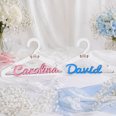 Cabides personalizados em madeira para Carolina e David com decoração floral ao fundo