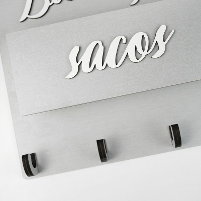 Suporte de parede em metal com ganchos e texto suacos em relevo
