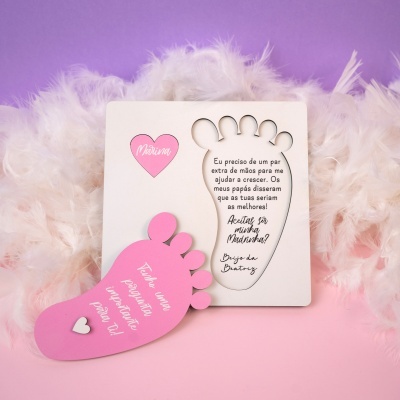 Quadros decorativos em forma de pés, um branco com texto e outro rosa, sobre fundo colorido com plumas brancas.
