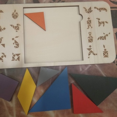 Tabuleiro de madeira com peças coloridas para montagem geométrica.