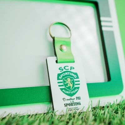 Chaveiro branco e verde com alça e aro metálico com texto e logotipo do Sporting Portugal