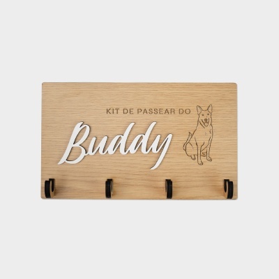 Placa de madeira clara com texto KIT DE PASSEAR DO Buddy e ilustração de um cão, com quatro ganchos pretos em baixo.