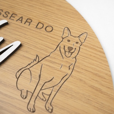 Placa redonda em madeira clara com gravação de cão e texto parcial SSEAR DO