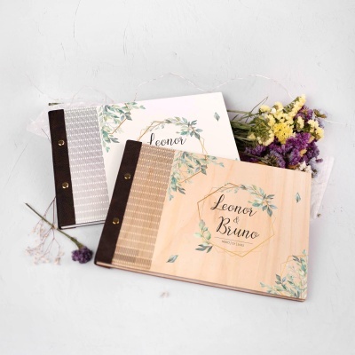 Álbuns de madeira decorados com folhas verdes e lombadas de couro castanho, com flores secas junto, texto Leonor e Leonor & Bruno MAIO | 07 | 2022