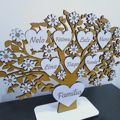 Árvore de família em madeira com nomes gravados em corações brancos e flores decorativas.