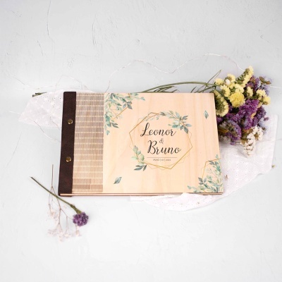 Livro de madeira com decoração floral e texto Leonor & Bruno MAIO | 07 | 2022 junto a flores secas amarelas, roxas e brancas
