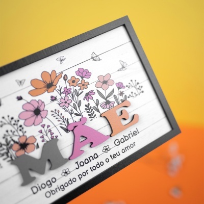 Quadro decorativo com flores coloridas e texto em português em fundo branco e moldura preta